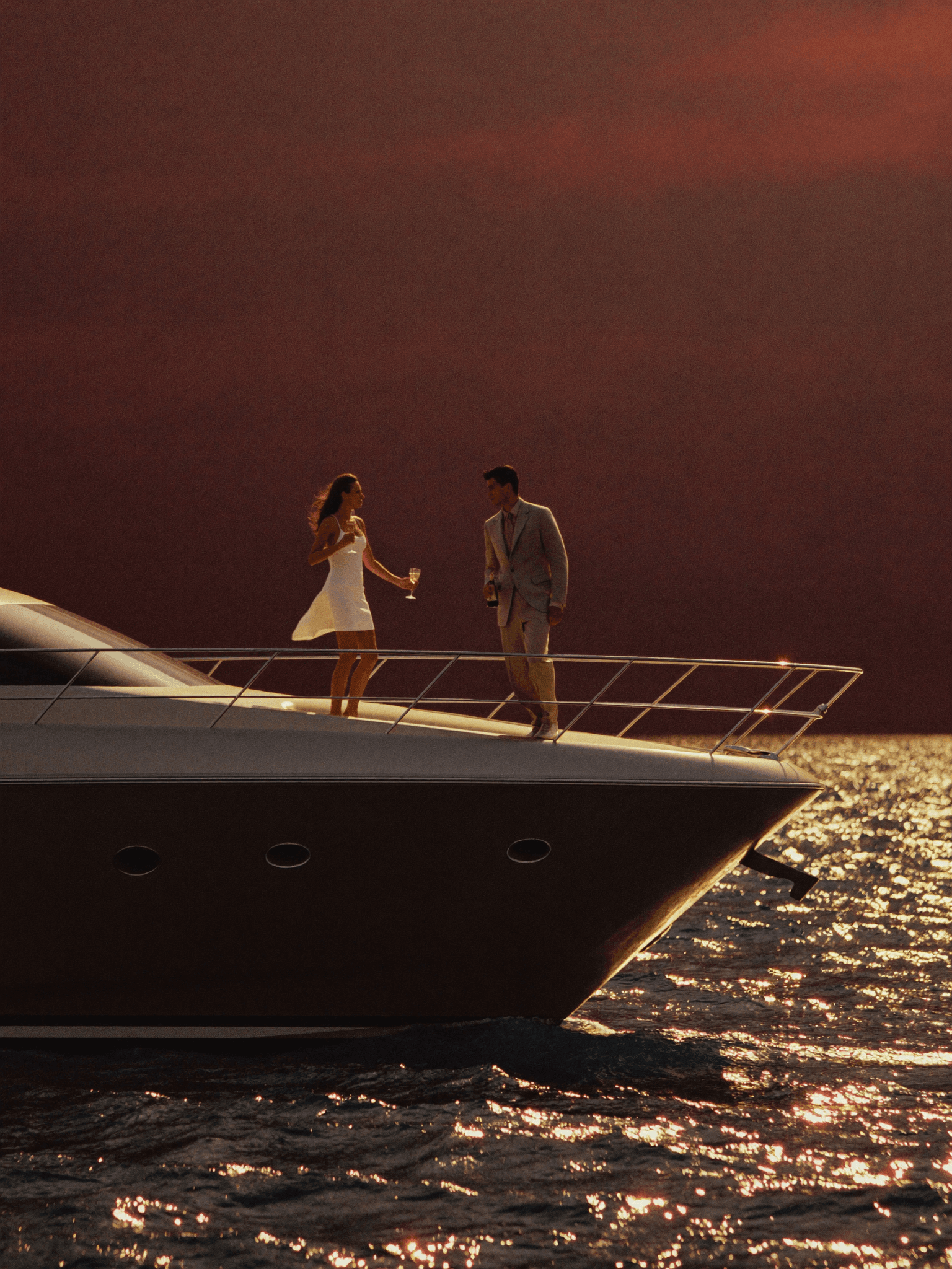 A couple with champagne at the bow of a luxury yacht at sunset